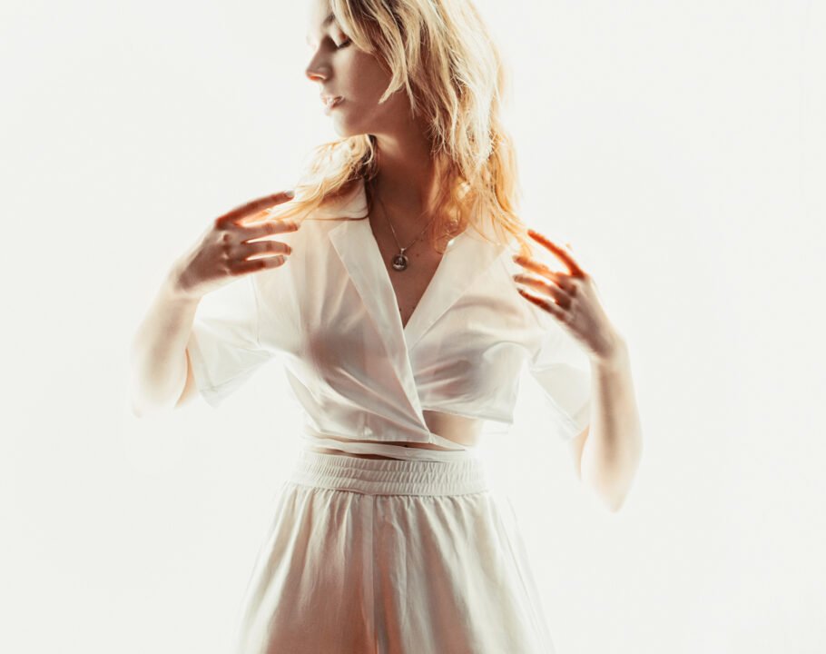 Blonde woman wearing white in front of white background