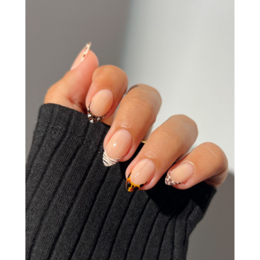 A close-up of a woman's hand with a mixed-print french manicure