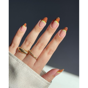 A close up of a woman's hands with fingernails with neon print and tortoise shell prints